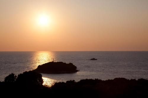 a sunset over the ocean with a rock in the water at Apartments Ruby in Funtana
