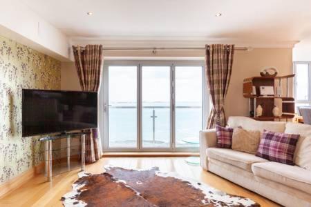 a living room with a couch and a flat screen tv at Blue Pool View in Portrush