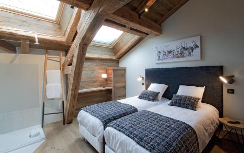 une chambre avec deux lits dans une pièce avec des plafonds en bois dans l'établissement Odalys Chalet Le Lys, à Les Deux Alpes