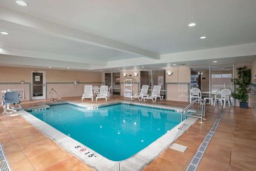a pool in a hotel with chairs and a table at Comfort Suites Foley - North Gulf Shores in Foley