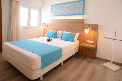 
a bedroom with a white bed and a blue comforter at Cala Llenya Resort Ibiza in Cala Llenya
