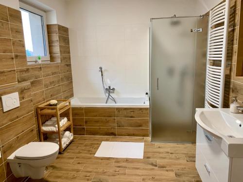 a bathroom with a tub and a toilet and a sink at Penzion Holín u Prachovských skal in Jičín
