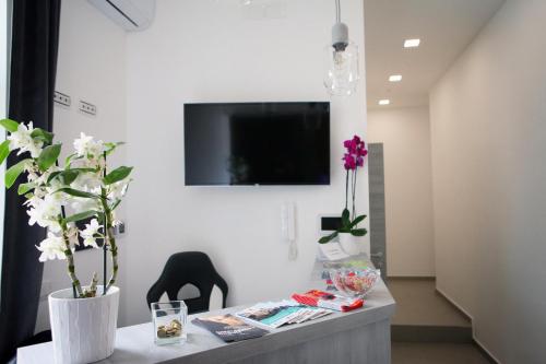 a room with a table with flowers and a tv on a wall at Le Corti del Re in Naples