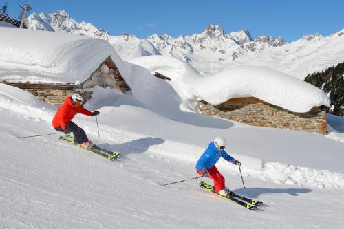 two people are skiing down a snow covered slope at Belavita B&B in Ischgl