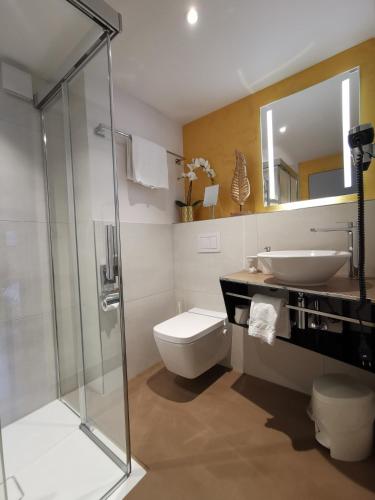 a bathroom with a sink and a toilet and a mirror at Hotel Brienzersee in Ringgenberg