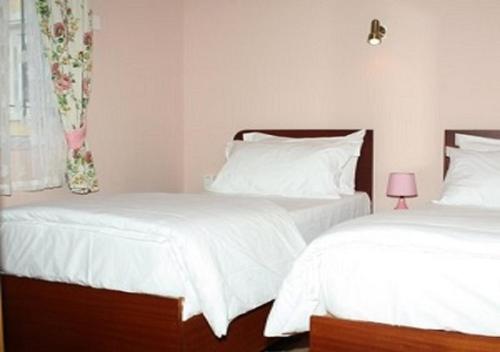 una camera con due letti con lenzuola bianche e una finestra di Trou Aux Biches Self Catering Apartment a Trou aux Biches