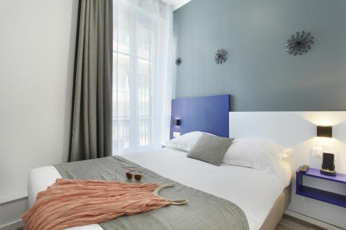 a bedroom with a large white bed and a window at Hôtel Alcôve Nice in Nice