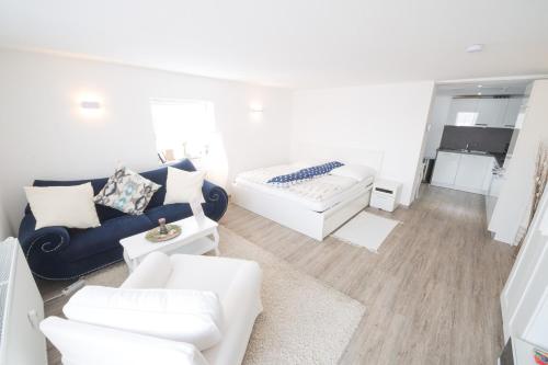 Perfect Apartment near Opera في بايروث: غرفة معيشة بها أريكة زرقاء وأثاث أبيض