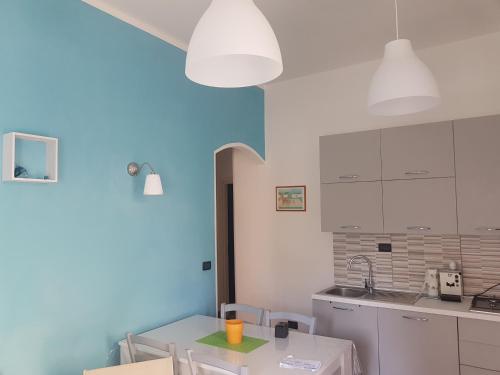 Casa Marcella في سترارو: مطبخ فيه دواليب بيضاء وحائط ازرق