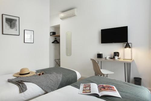 a bedroom with a bed with a hat and a desk at Hôtel Alcôve Nice in Nice