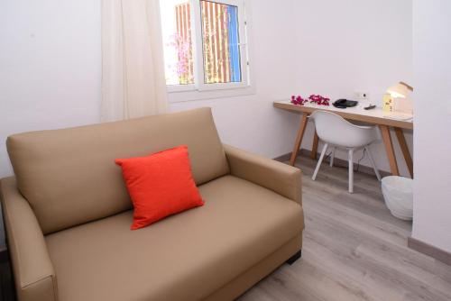 a couch with a red pillow on it in a room at Cala Llenya Resort Ibiza in Cala Llenya