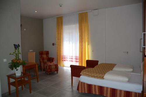 a bedroom with a bed and a chair and a window at Alpina home in Rosenheim