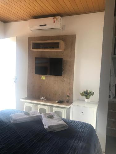 a bedroom with a bed and a tv on a wall at Chalé Temporada Porto dos Lençóis - Lençóis Maranhenses in Barreirinhas