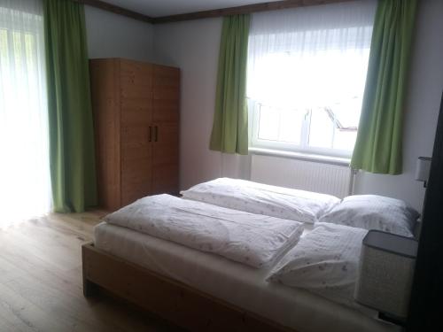 Duas camas num quarto com cortinas verdes e uma janela. em Ferienhaus Mendlingbauer em Lassing