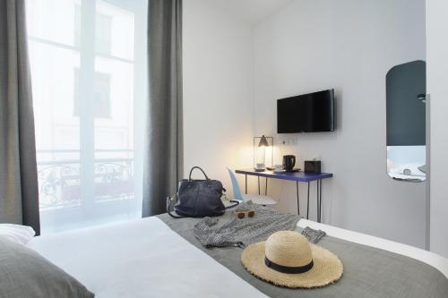 a hotel room with a bed with a hat on it at Hôtel Alcôve Nice in Nice