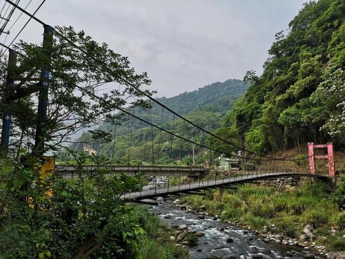 a bridge over a river next to a mountain at Sunlight Forest in Dahu