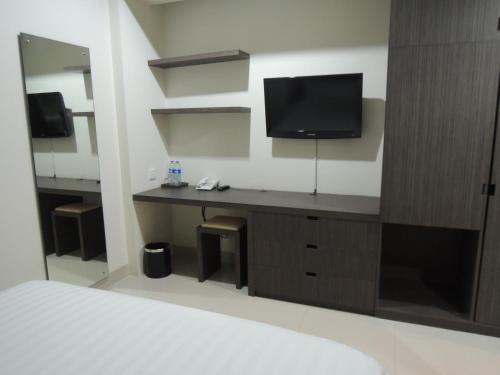 1 dormitorio con escritorio y TV en la pared en Harlys Residence, en Yakarta