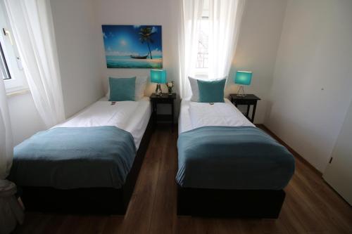 2 Einzelbetten in einem Zimmer mit 2 Fenstern in der Unterkunft Apart Hotel Paradies in Bad Salzschlirf