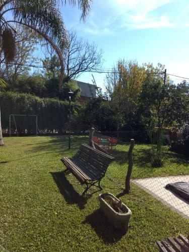 a park bench sitting in the grass with a planter at QUINTA EN OPEN DOOR-LUJÁN in Luján