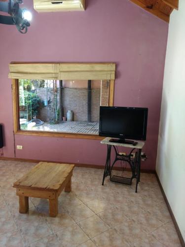 a living room with a tv and a table and a bench at QUINTA EN OPEN DOOR-LUJÁN in Luján