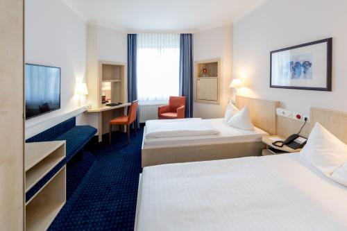a hotel room with two beds and a television at IntercityHotel Magdeburg in Magdeburg