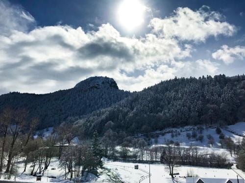 a snow covered mountain with the sun in the sky at Hôtel Les Mouflons in Le Mont-Dore