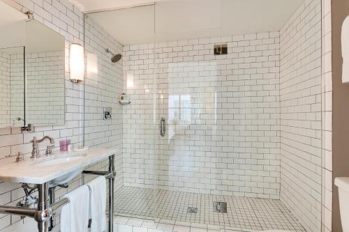 a white tiled bathroom with a shower and a sink at Clinton Hotel South Beach in Miami Beach
