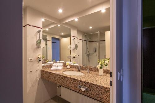 a bathroom with two sinks and a mirror at Globana Airport Hotel in Schkeuditz