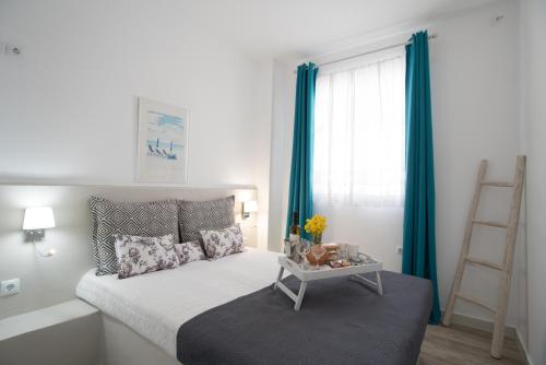 a bedroom with a bed with blue curtains and a ladder at Homebase in Parikia