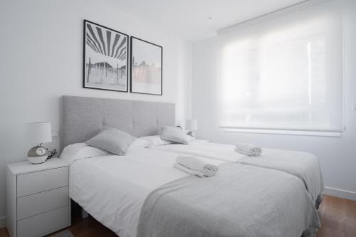 two beds in a white bedroom with two towels on them at GOXUE HOME in Donostia-San Sebastián