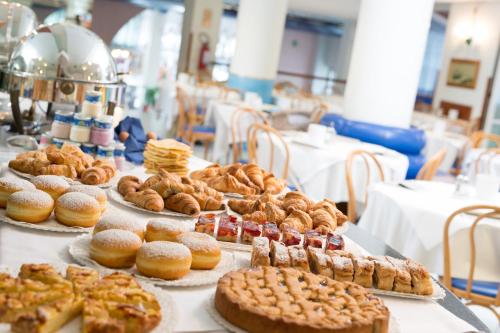 una mesa con varios pasteles y pasteles y otros productos de repostería en Hotel Astro, en Lignano Sabbiadoro