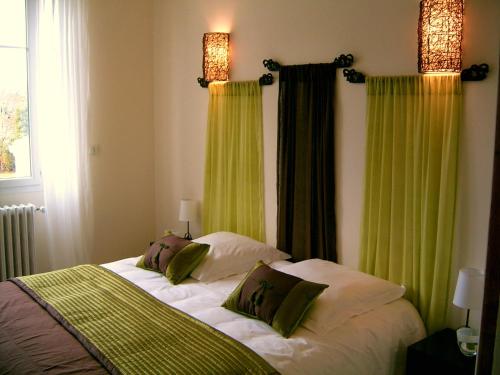 a bedroom with a bed with green curtains at La Villa Camille in La Creche