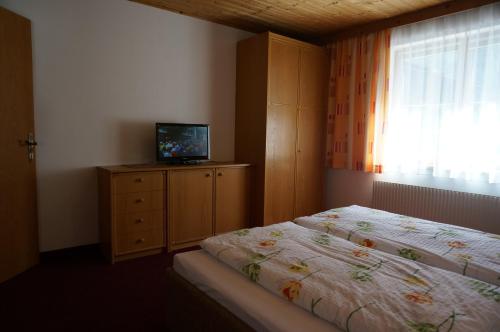 1 dormitorio con 2 camas y un tocador con TV en Haus Birgit en Pettneu am Arlberg