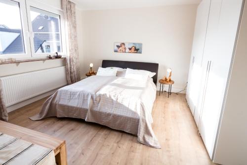 a white bedroom with a bed and a window at Glockenstuhl @Conny's in Brilon