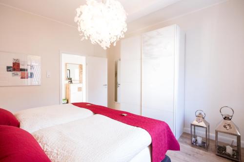a bedroom with a white bed and a chandelier at Glockenstuhl @Conny's in Brilon