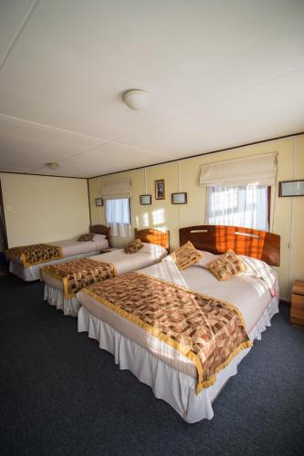 a hotel room with four beds in it at Hostal Alcázar in Puerto Natales