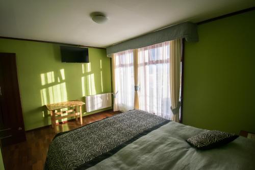 a bedroom with green walls and a bed and a table at Hostal Alcázar in Puerto Natales
