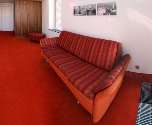 an orange couch in a room with a red carpet at Business Hotel Ambio Gleisdorf in Gleisdorf