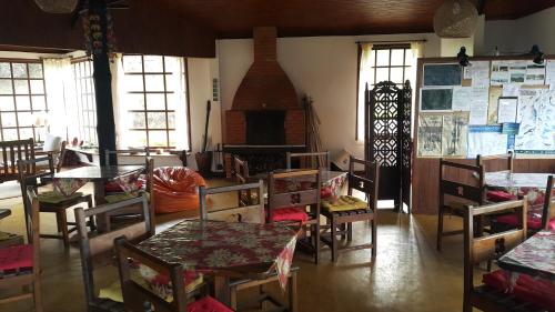 a dining room with tables and chairs and a fireplace at Pousada do Morro Verde in Carvalhos