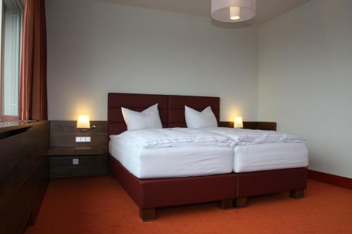 a bedroom with a large bed with two lamps at Business Hotel Ambio Gleisdorf in Gleisdorf