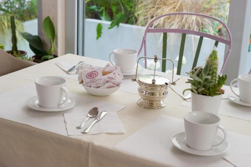 a table with white cups and saucers on it at Hotel Torino in Parma