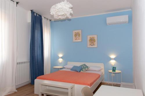 a small room with a white bed and blue walls at Mondello Beach Rooms - by the sea in Mondello