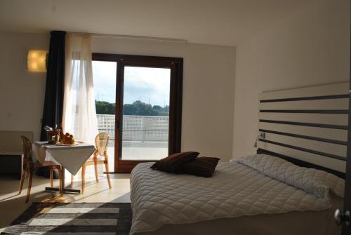 Schlafzimmer mit einem Bett, einem Tisch und einem Fenster in der Unterkunft Althea Palace Hotel in Castelvetrano Selinunte