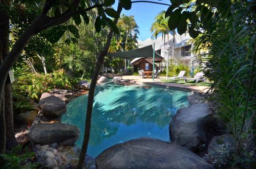 a swimming pool in a yard with rocks and a house at Raintrees Moffat Beach in Caloundra