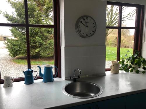 a kitchen counter with a sink and a clock on a wall at Bed & coffee Hjørring in Hjørring
