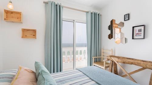 um quarto com uma cama e uma janela com vista para o oceano em Vila Varanda by Sevencollection em Salema