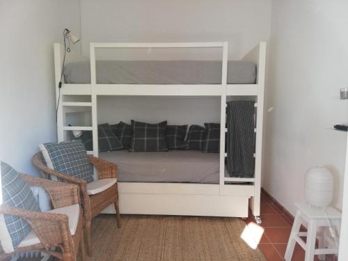 a white bunk bed in a room with a chair at Casa Típica Algarvia in Cabanas de Tavira