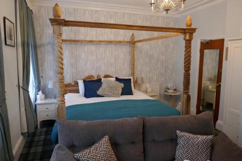 a bedroom with a bed with a wooden frame and a couch at The Boundary in Scarborough