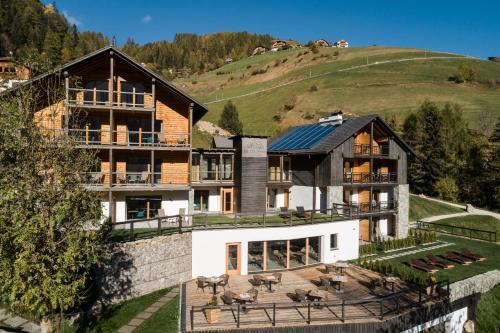a large house with a hill in the background at Les Dolomites Mountain Lodges in San Martino in Badia