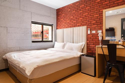 台北的住宿－龍山旅社，一间卧室设有一张床和砖墙